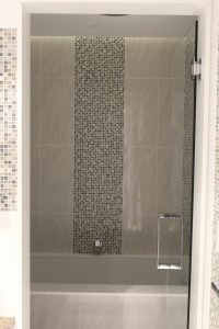 In this apartment, utility meets high design in an elegant fashion. The subtle, yet vibrant vertical mosaic leads the homeowner into the combination bath and shower room.
