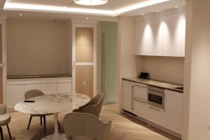 This room was turned into a common area for meeting space. But the finishes are anything but common. Marble imported from Spain adorns the custom cabinetry and sits atop a chevron pattern floor. Unique lighting sets the tone of the room.